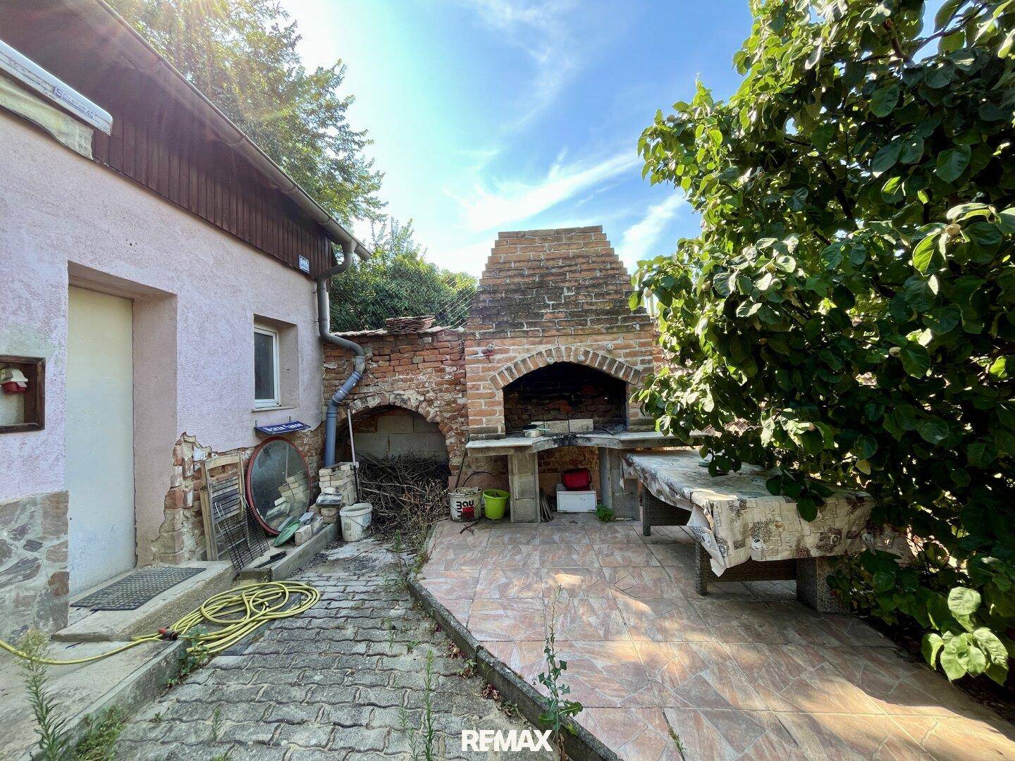 Großer gemauerter Grillbereich im Freien mit Arbeitsflächen und Fliesenboden.