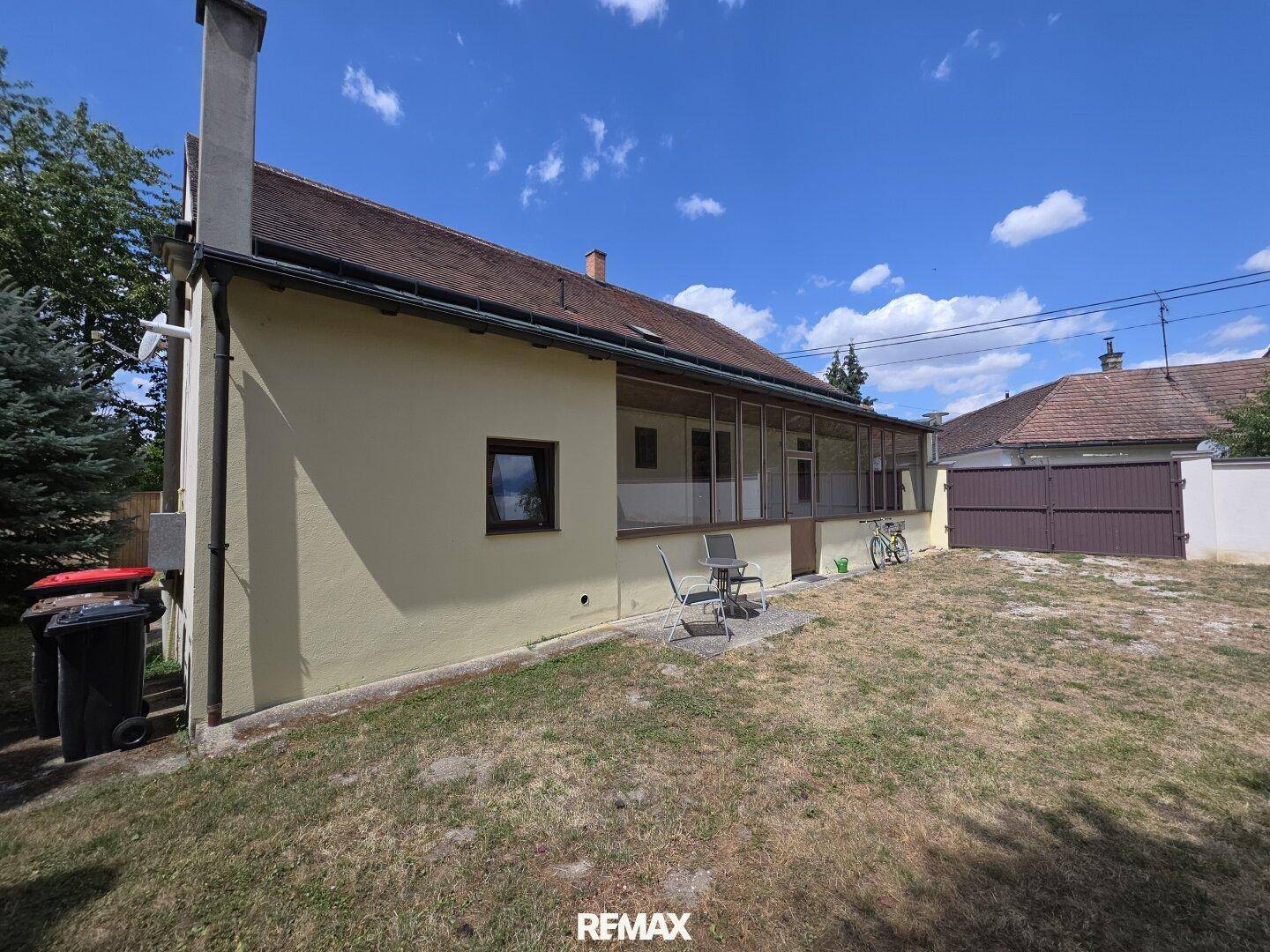 Seitenansicht des Hauses mit überdachter Loggia und kleinem Gartenbereich.