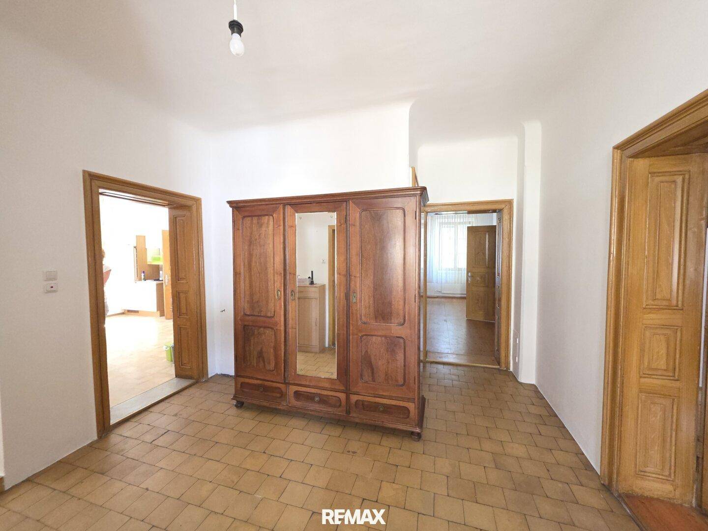 Heller Flur mit großem Holzschrank und traditionellem Fliesenboden.