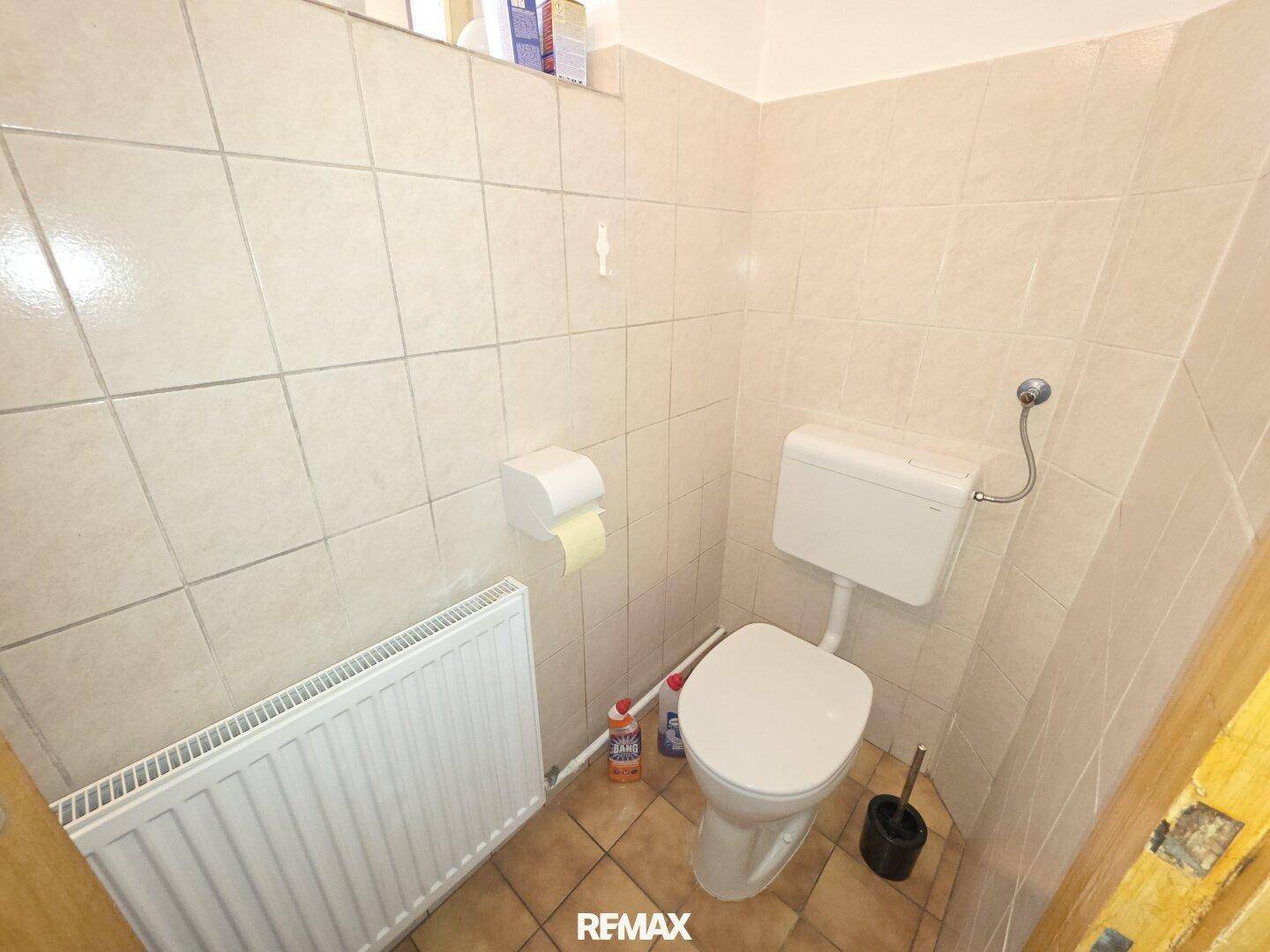 Separate Toilette mit Fliesenboden und Heizkörper, in gutem und sauberem Zustand.