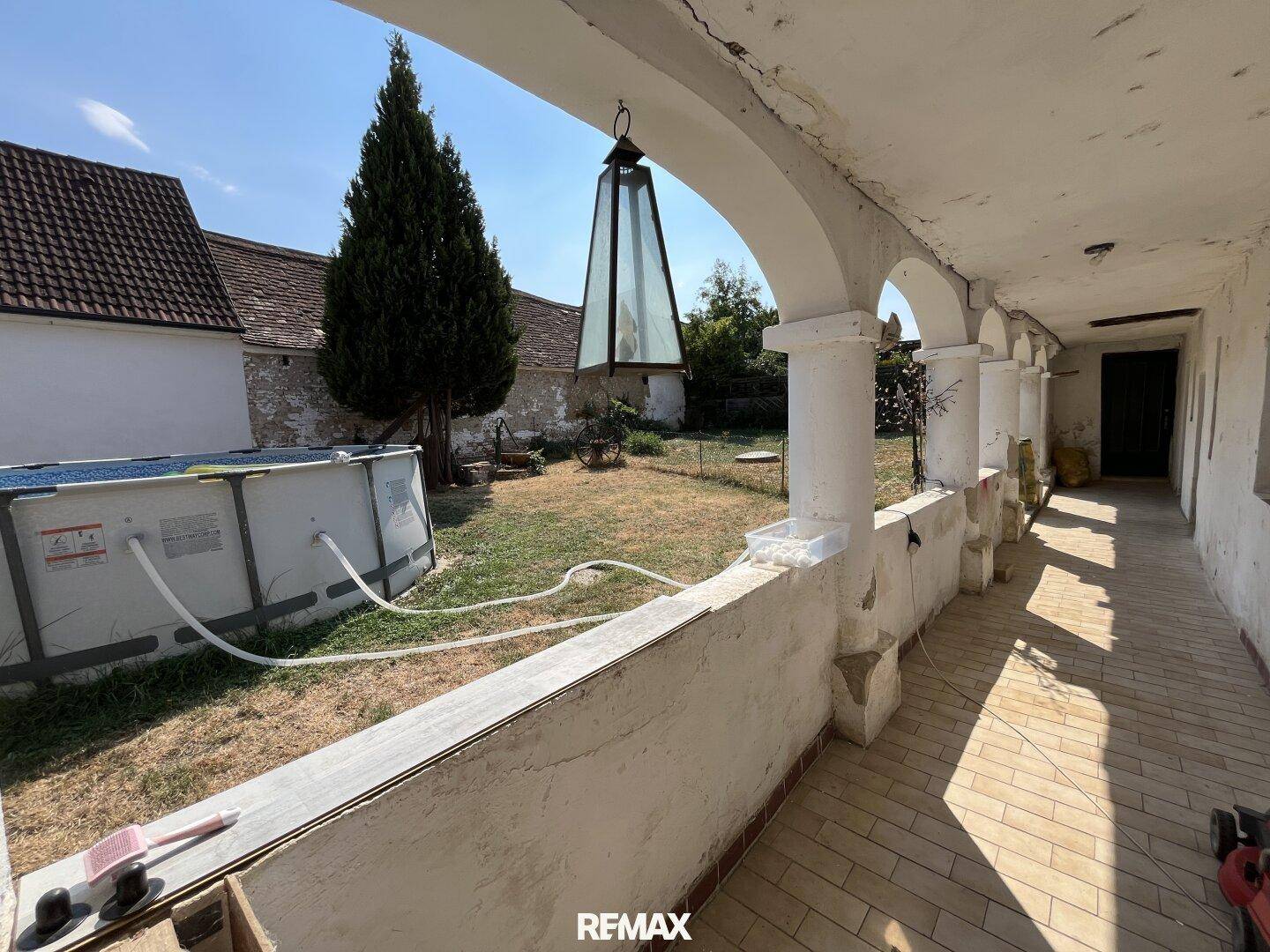 Überdachter Arkadengang mit Blick auf den Garten und den aufgestellten Pool.