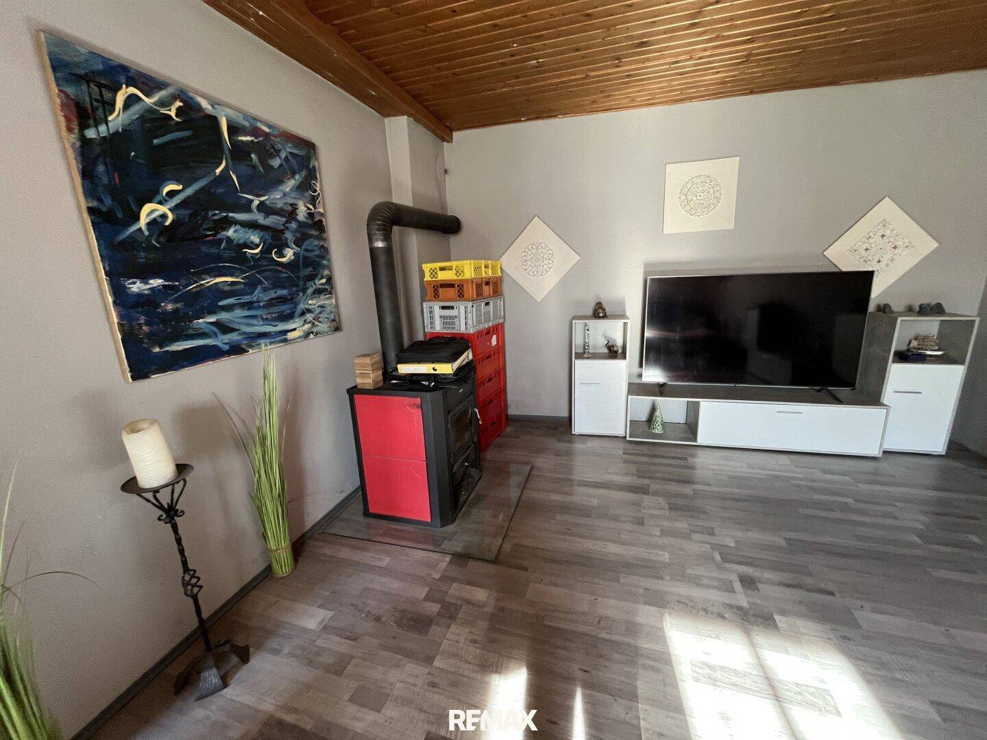 Gemütliches Wohnzimmer mit Holzofen, Holzboden und einer Holzdeckenverkleidung.