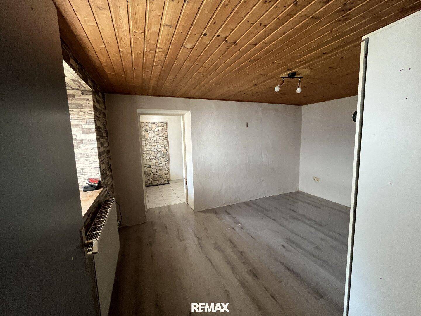 Innenraum mit Holzboden, Holzdeckenverkleidung und einer Wand mit Steinoptik.