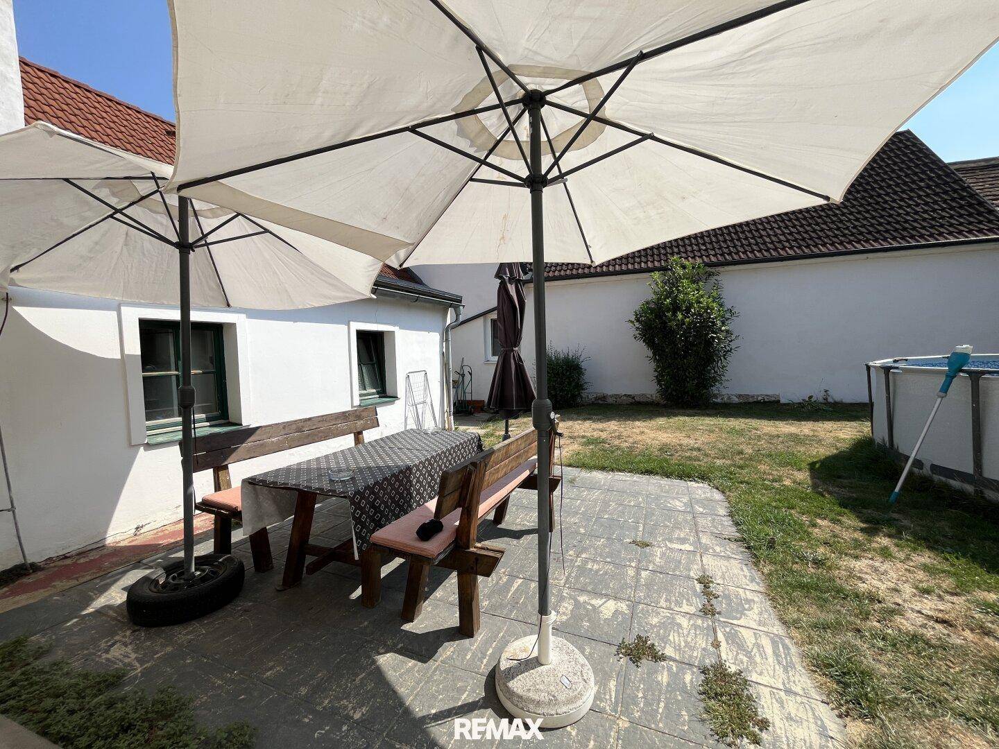 Gemütliche Terrasse mit Sitzgelegenheiten und Sonnenschirmen, angrenzend an einen Gartenbereich.