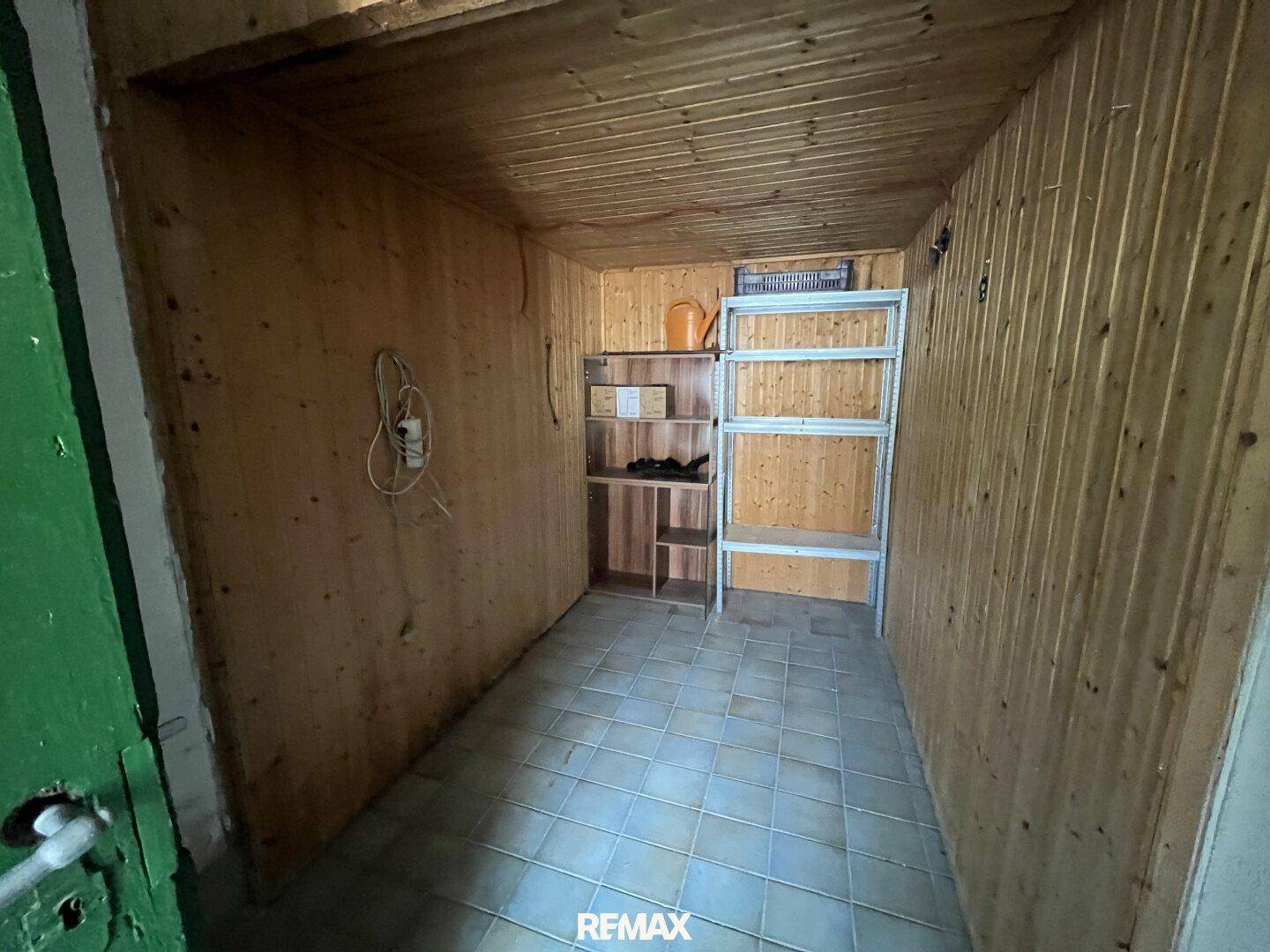 Abstellraum mit Holzverkleidung an Wänden und Decke, sowie Regalen für Lagerung.