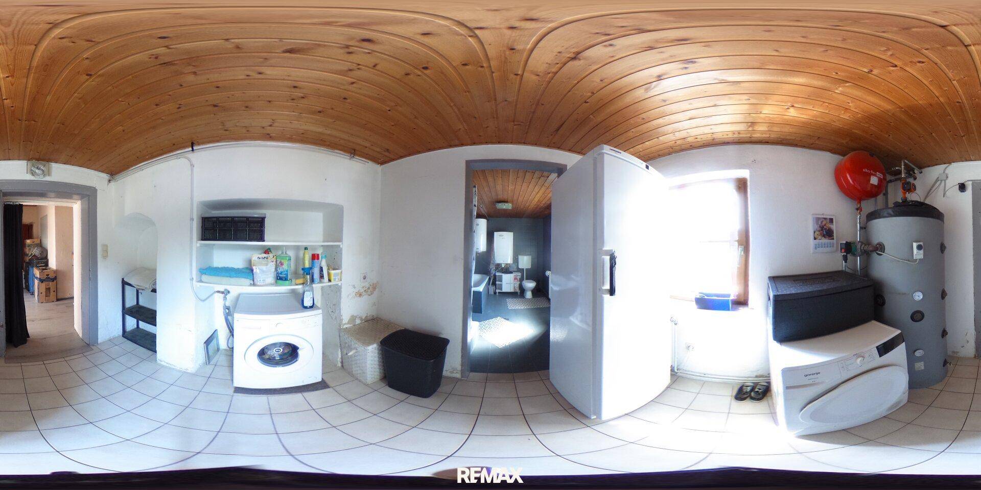 Praktischer Hauswirtschaftsraum mit Waschmaschine, Trockner, Kühlschrank und Warmwasserbereiter.