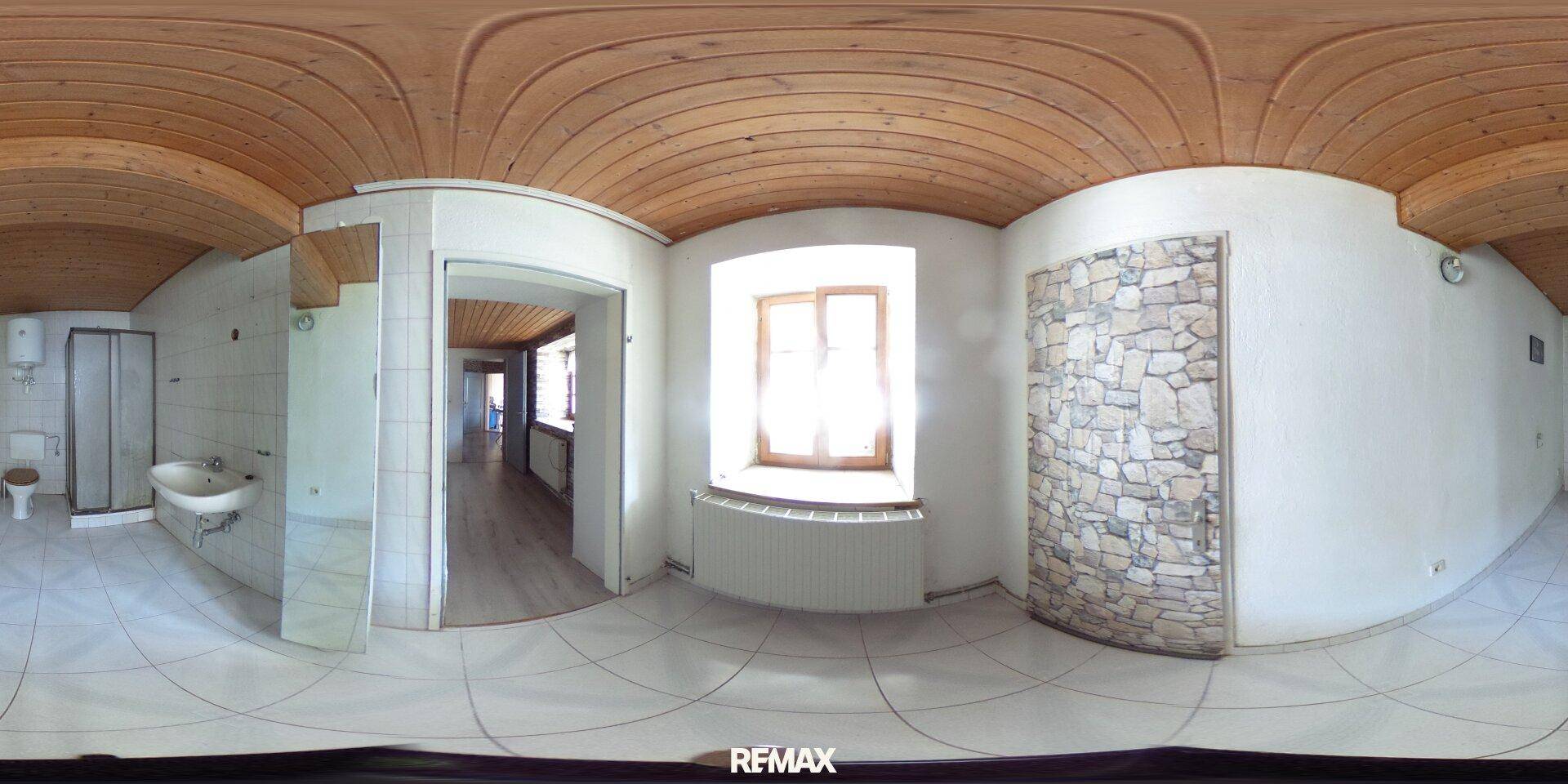 Helles Badezimmer mit WC, Waschbecken und Fliesenwänden, beleuchtet durch ein Fenster.