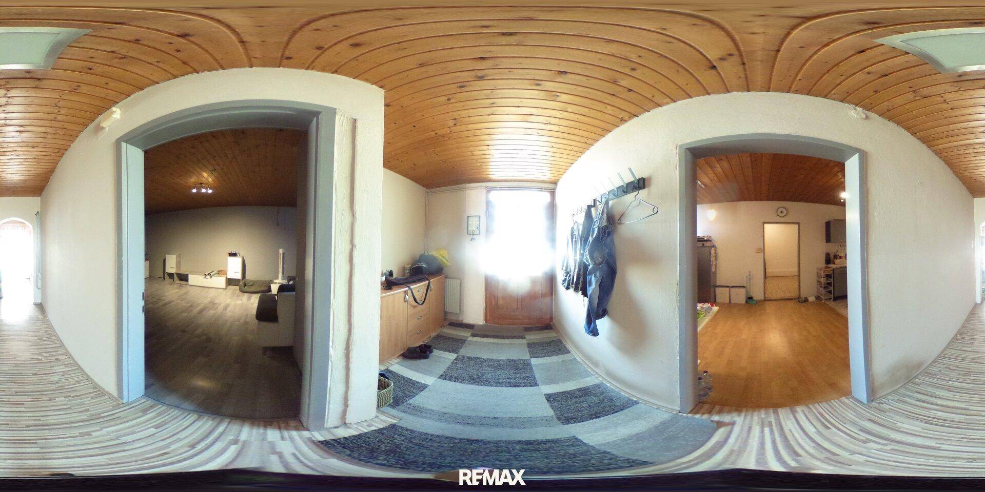 Panoramaansicht eines Flurs mit Holzdeckenverkleidung, Teppichboden und Zugang zu weiteren Räumen.
