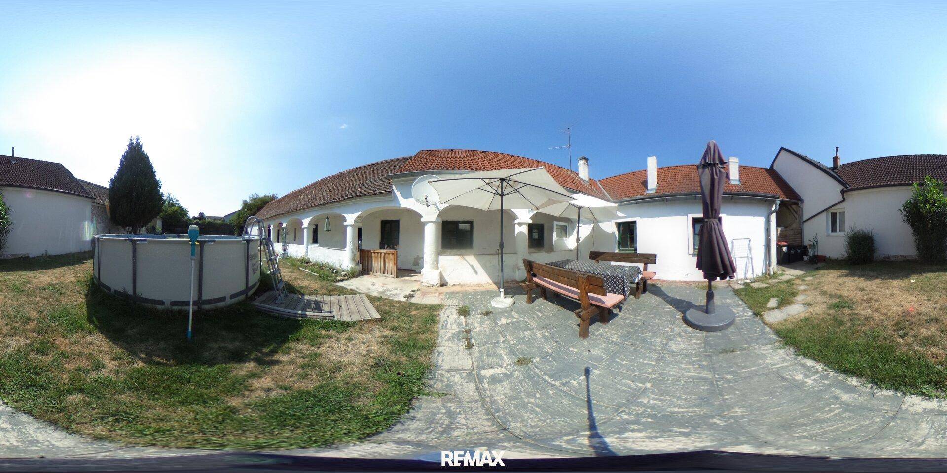 Panoramaansicht des Gartens mit aufgestelltem Pool, Terrasse und der Rückseite des Hauses.