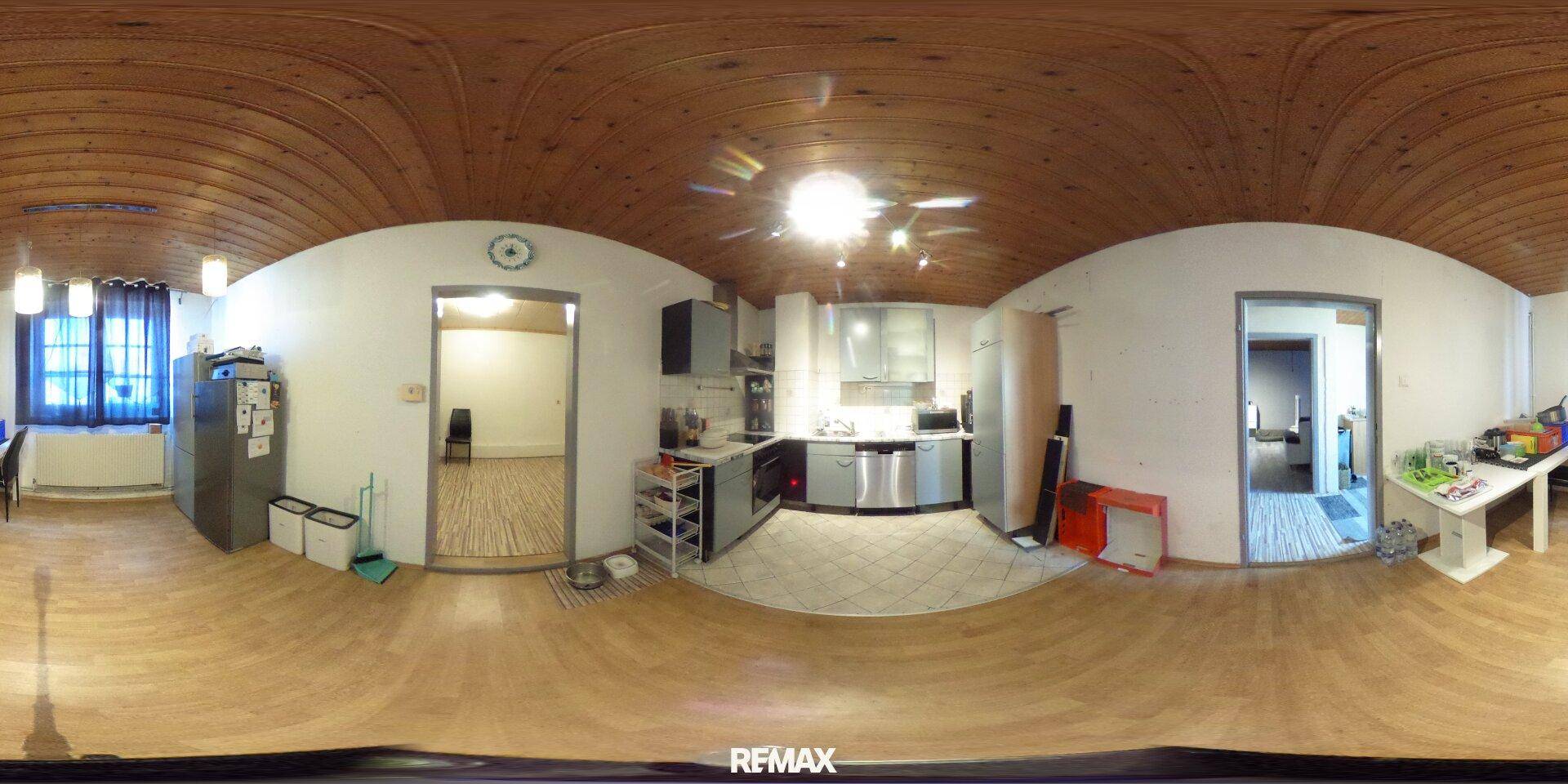Panoramaansicht der Küche mit grauen Schränken, Fliesenboden und angrenzenden Räumen.