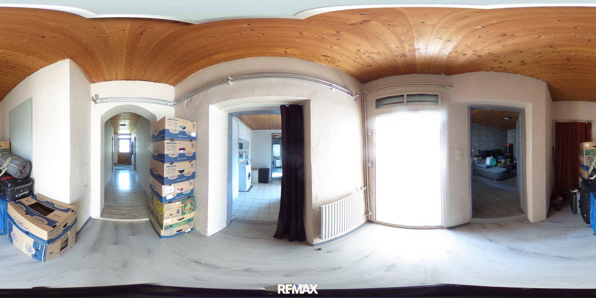 Langer Flur mit Holzbalkendecke und Zugang zu verschiedenen Räumen, mit natürlichem Lichteinfall.