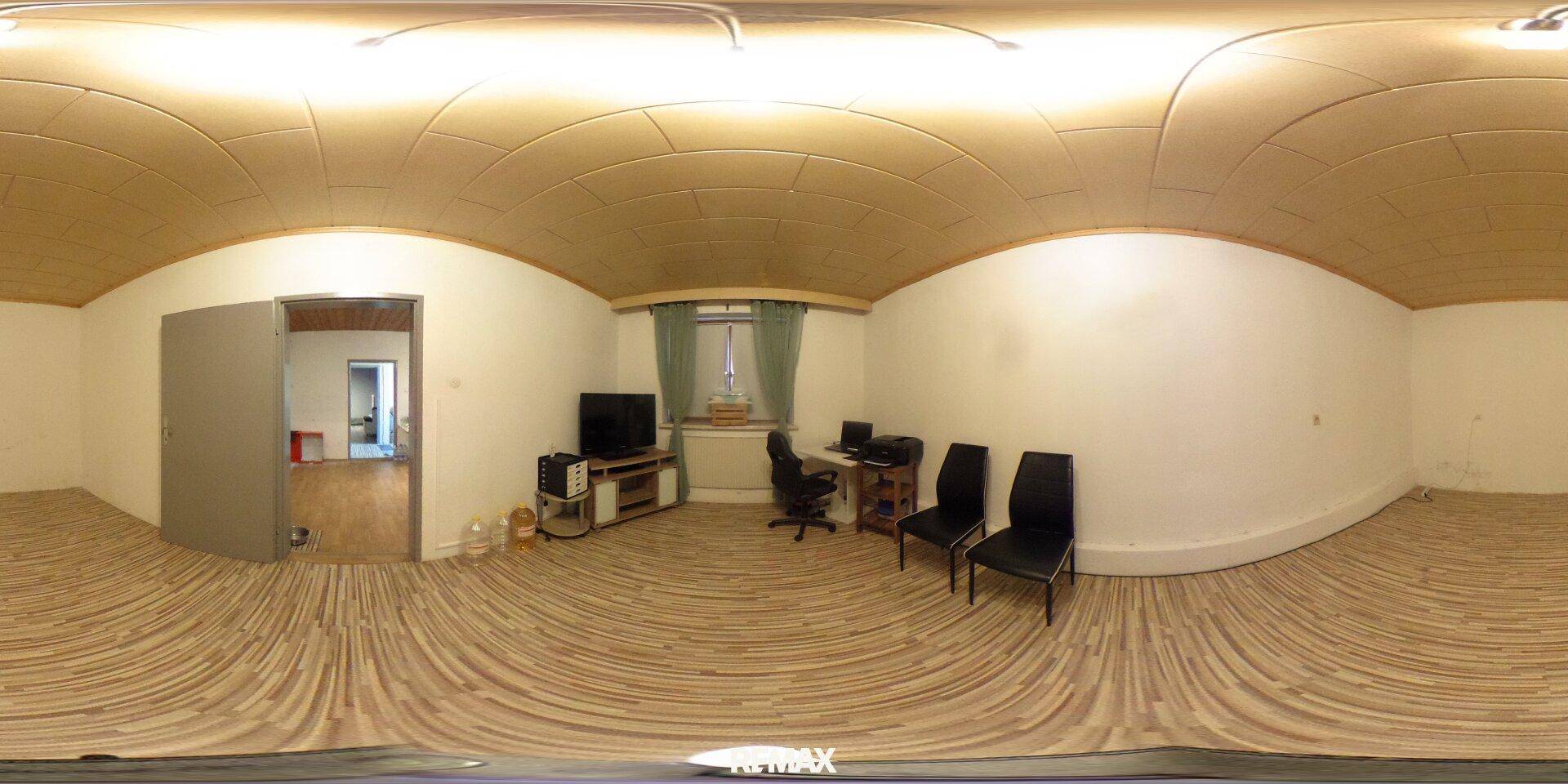 Helles Zimmer mit Schreibtisch, Bürostuhl und Holzdeckenverkleidung, ideal als Arbeitszimmer nutzbar.