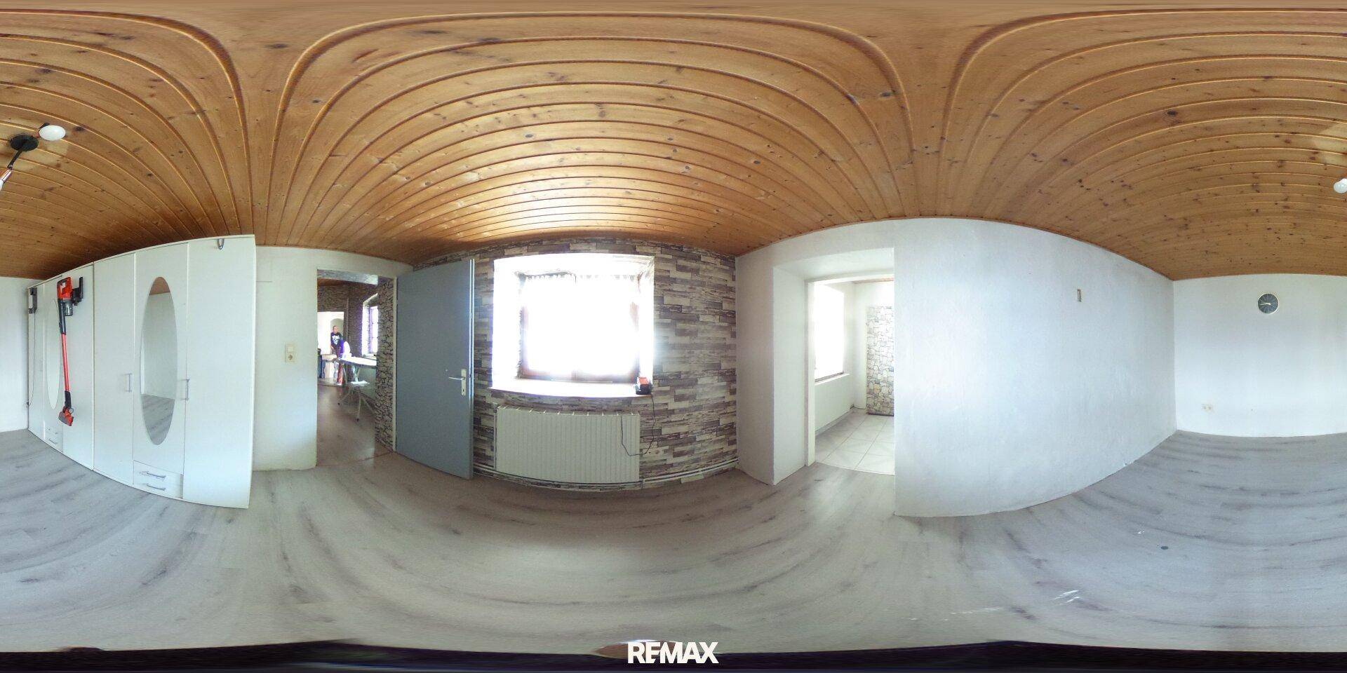 Heller Flur mit Einbauschränken, Fenster und einer Wand mit Steinoptik-Tapete unter Holzdecke.
