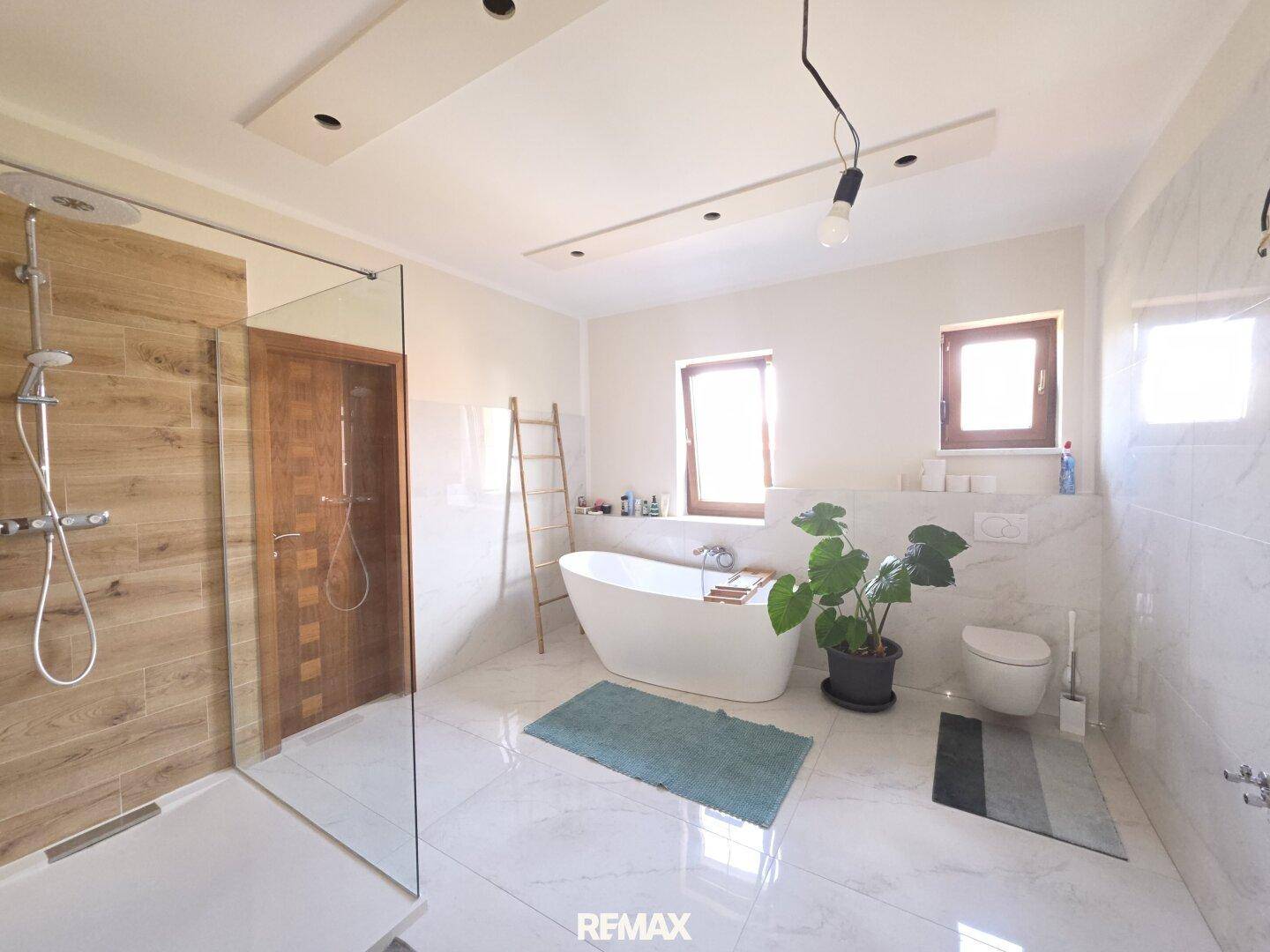 Modernes Badezimmer mit freistehender Badewanne, großer begehbarer Dusche und zwei Fenstern.