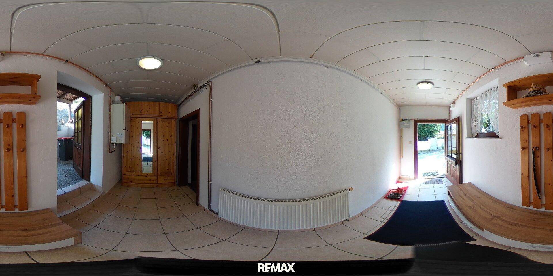 Heller Eingangsbereich mit Fliesenboden, Heizkörper und Holzbänken an den Wänden.