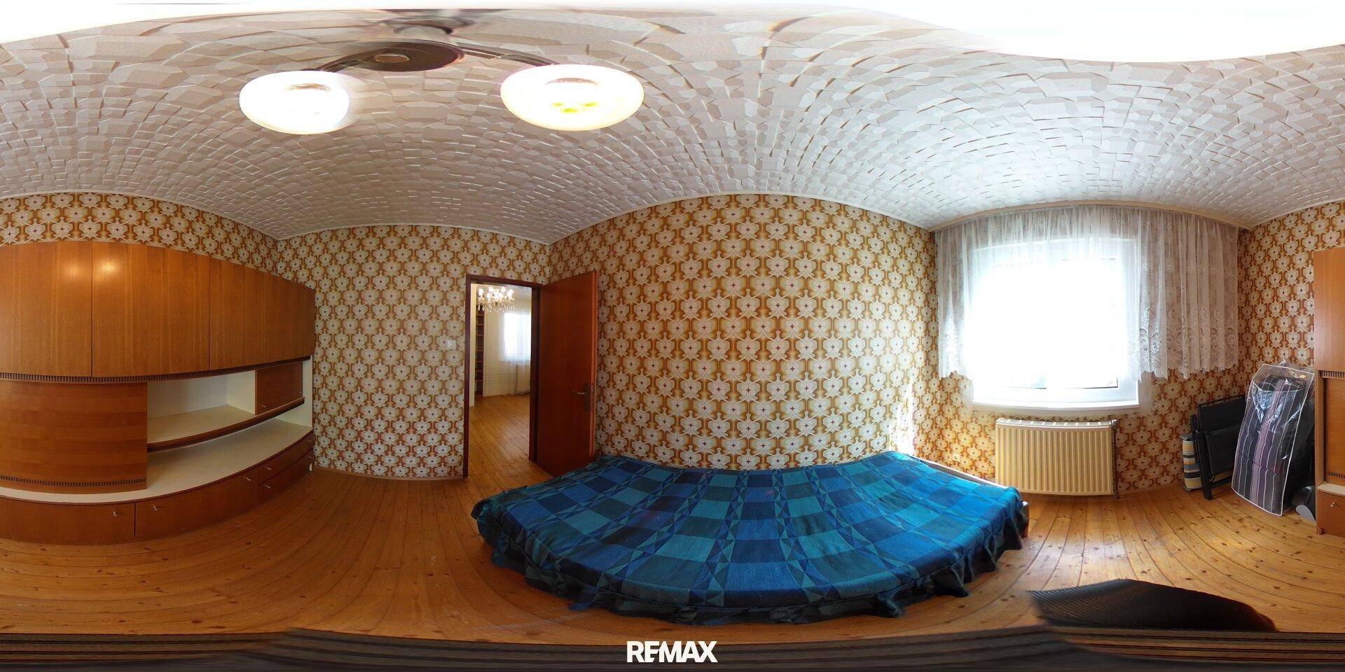 Schlafzimmer mit gemusterter Tapete, Parkettboden und großem Fenster für viel Tageslicht.