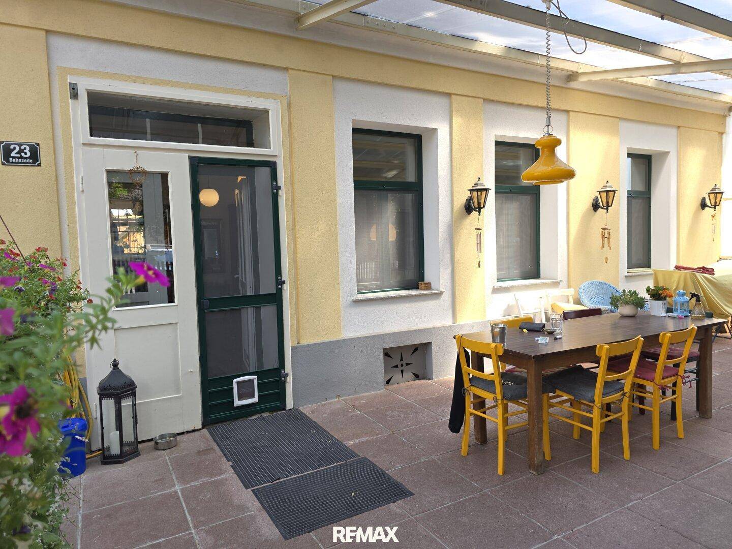 Detailansicht der Terrasse mit Esstisch, Stühlen und dem Eingangsbereich des Hauses.