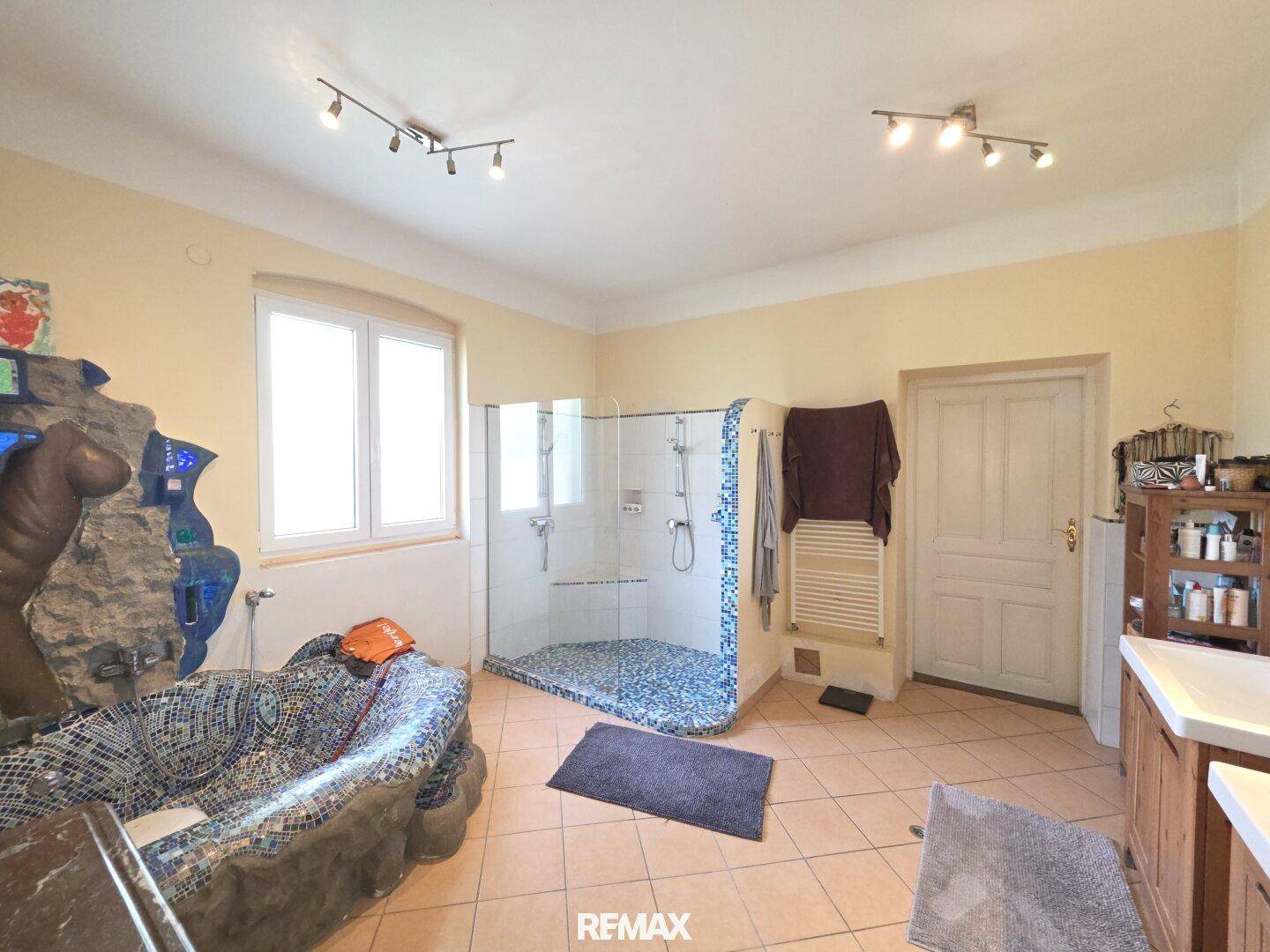 Geräumiges Badezimmer mit begehbarer Dusche, Fliesenboden und Fenster.