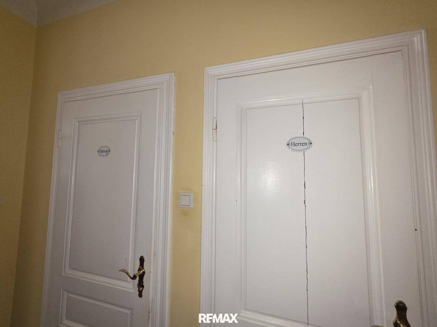 Zwei separate Toilettentüren, beschriftet mit "Damen" und "Herren", in einem Flur.
