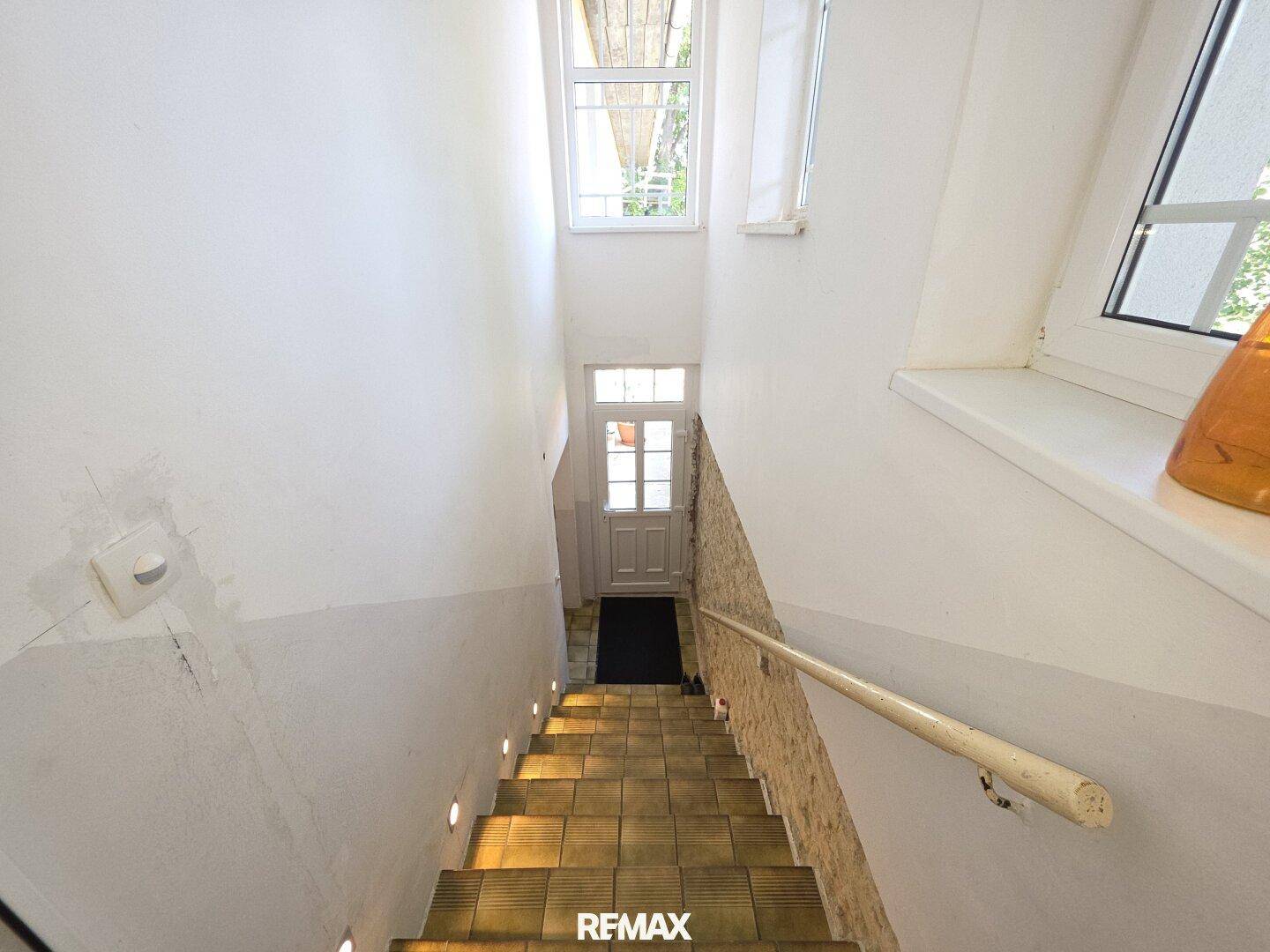 Treppenhaus mit gefliesten Stufen, Handlauf und natürlichem Lichteinfall von oben.