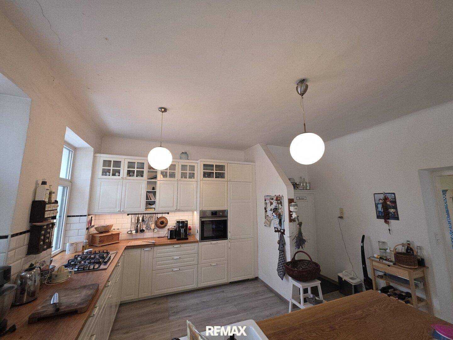 Geräumige Küche mit weißen Schränken, Holz-Arbeitsplatten und modernen Hängelampen.