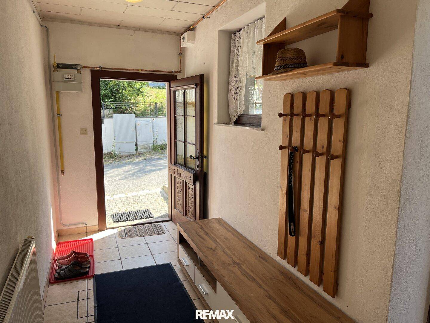 Heller Eingangsbereich mit Fliesenboden, Garderobe und Fenster zur Straße.