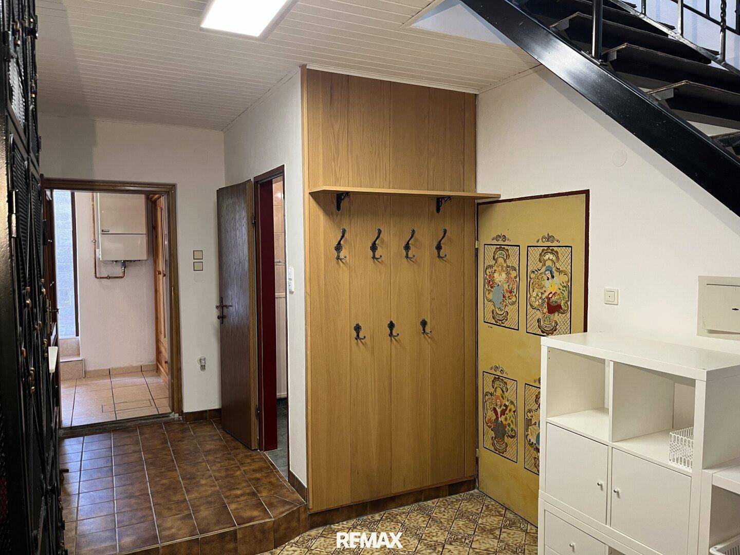 Flur mit Garderobe, Fliesenboden und Zugang zu verschiedenen Zimmern.