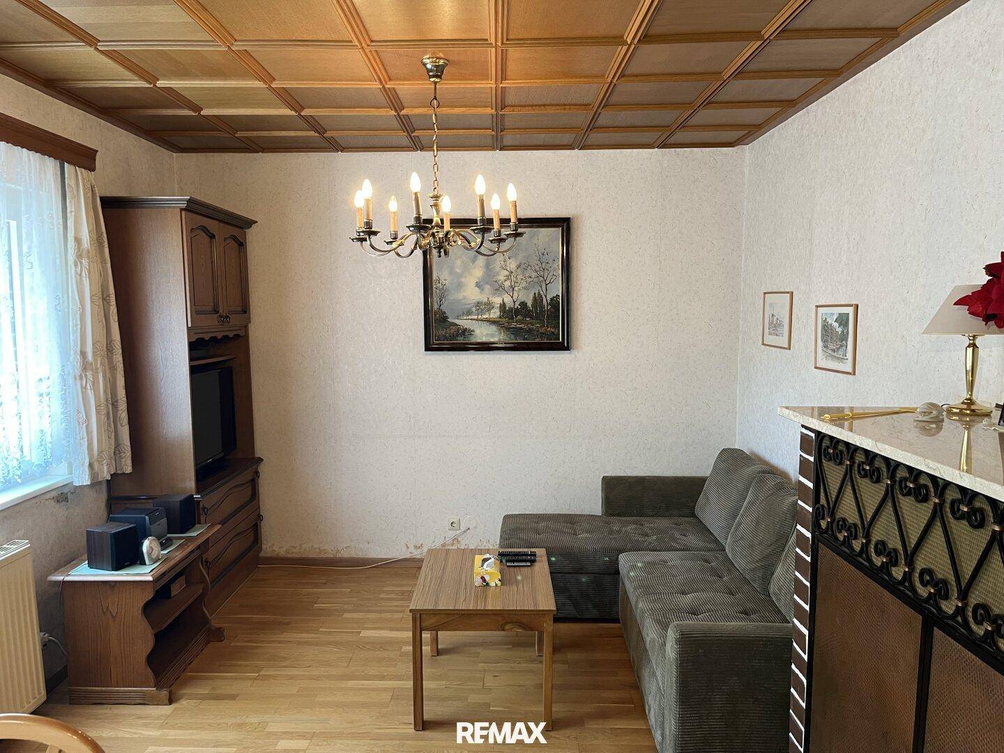 Gemütliches Wohnzimmer mit Holzboden, Holzdecke und traditioneller Einrichtung.