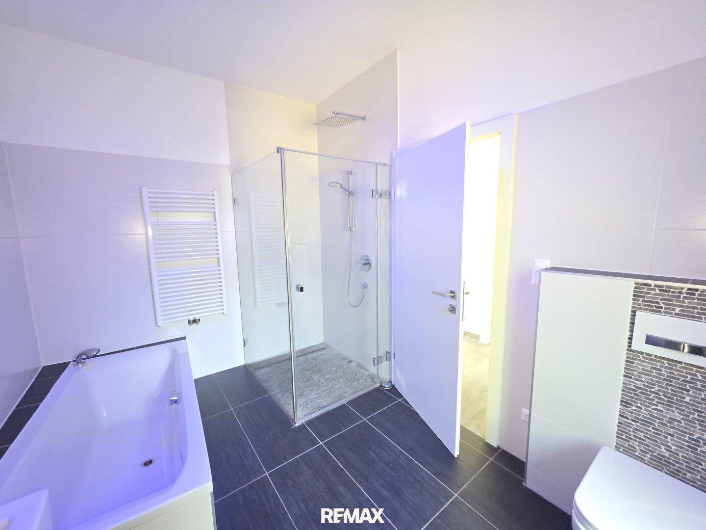Modernes Badezimmer mit begehbarer Dusche, Badewanne und beheiztem Handtuchhalter.