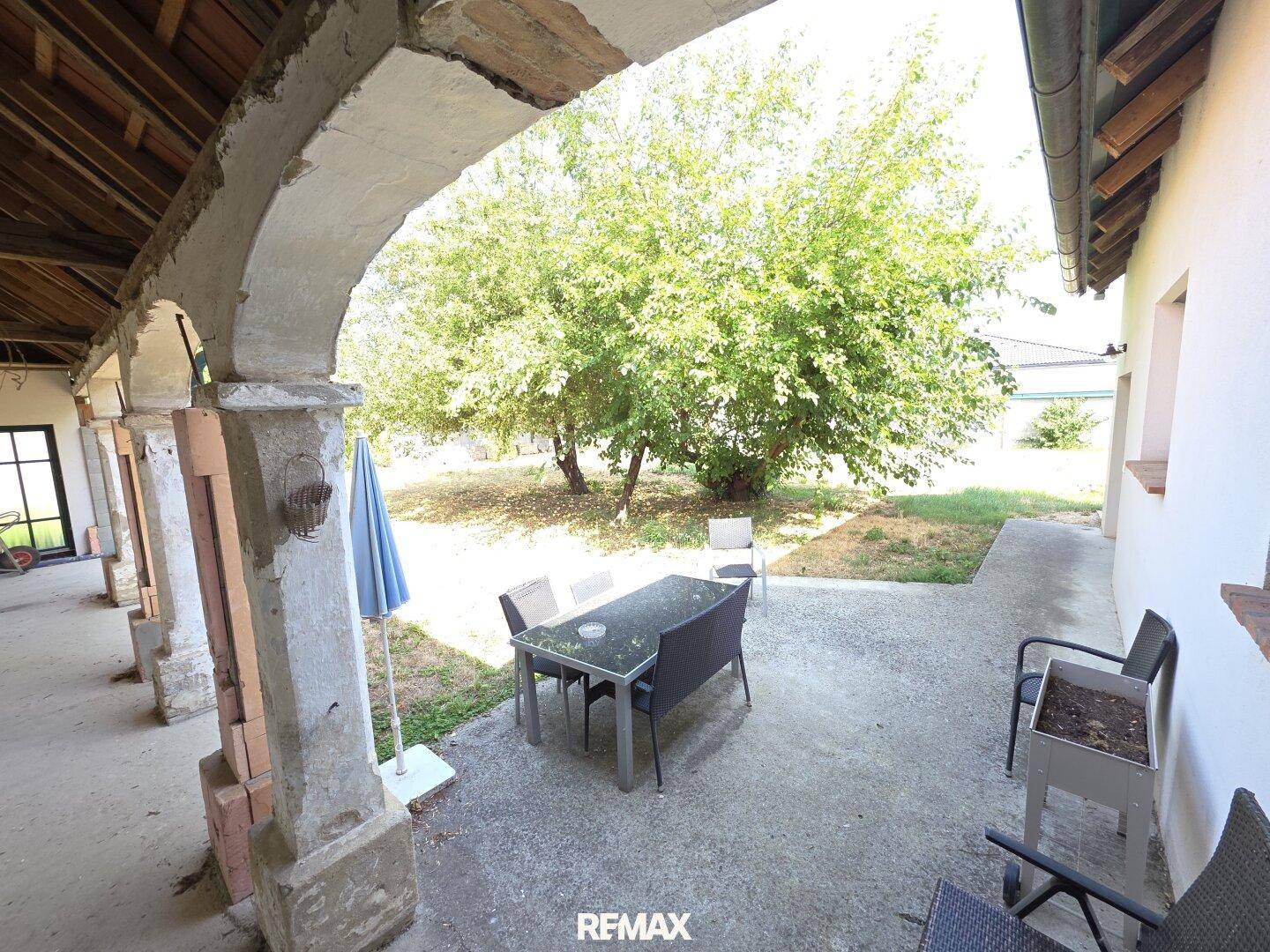 Überdachte Terrasse mit Sitzgelegenheiten und Blick auf den grünen Gartenbereich.
