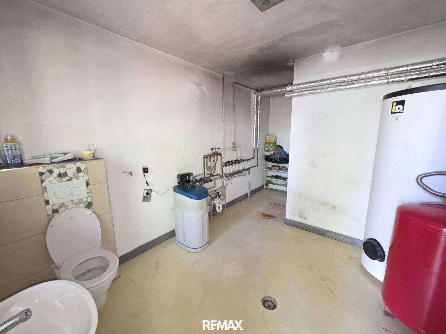 Hauswirtschaftsraum im Keller mit Warmwasserboiler, Sanitärinstallationen und Toilette.