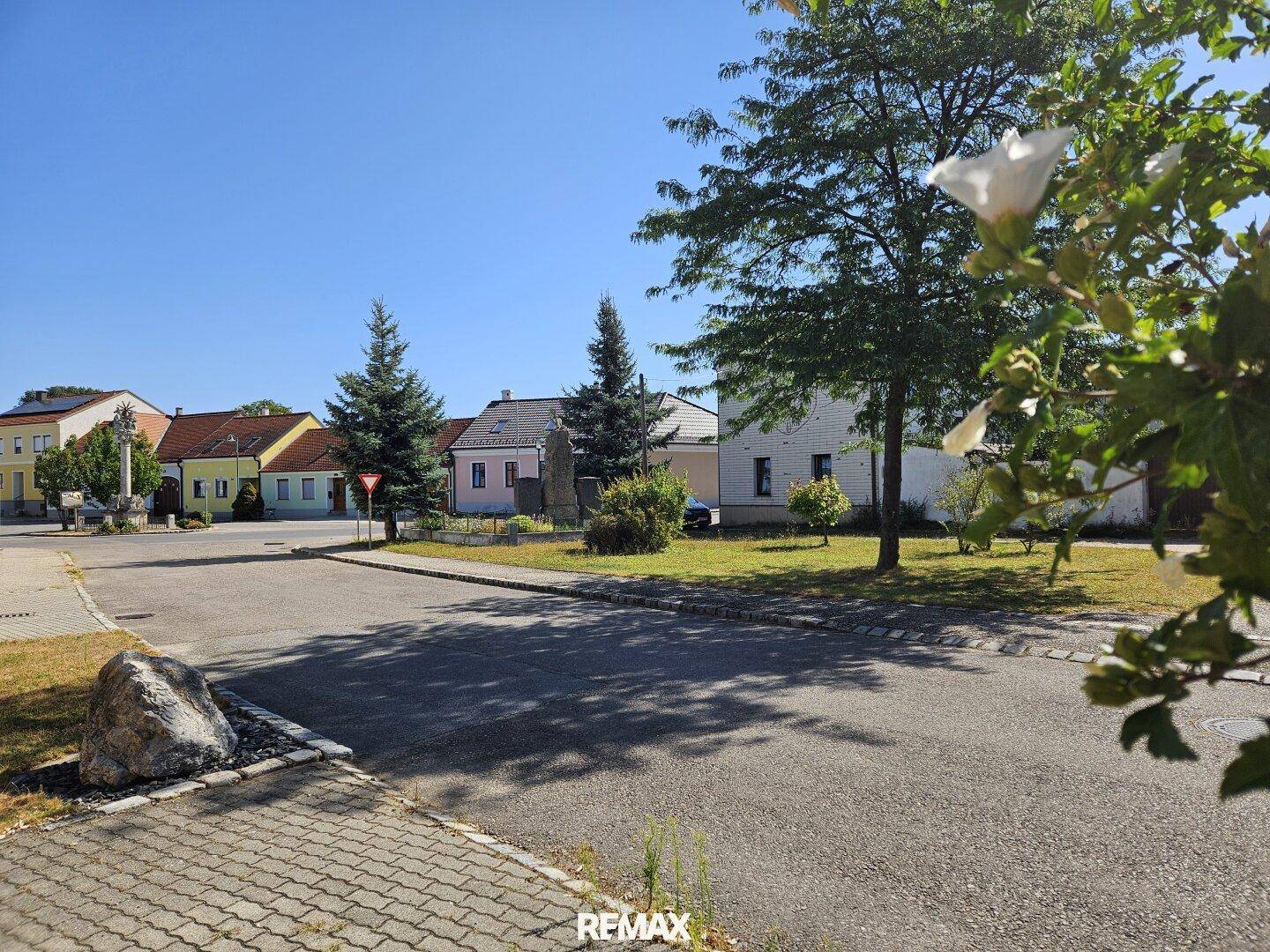 Blick auf die ländliche Umgebung mit einer Straße, Bäumen und weiteren Häusern im Hintergrund.