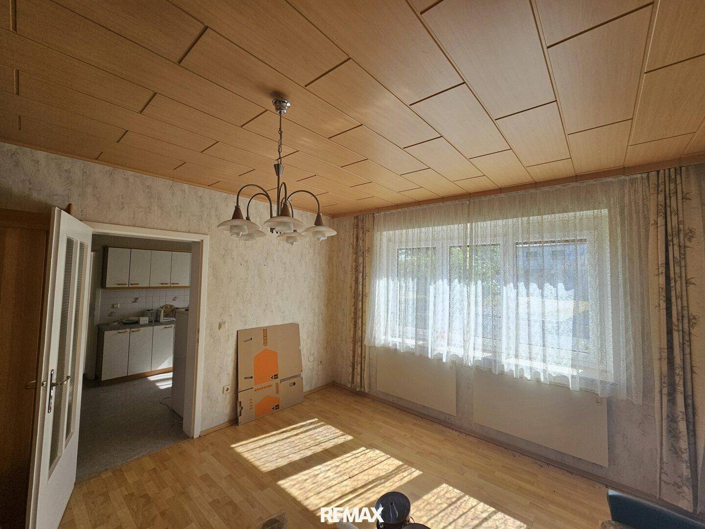 Helles Wohnzimmer mit großen Fenstern, Holzdecke und Parkettboden, bereit für eine Neugestaltung.