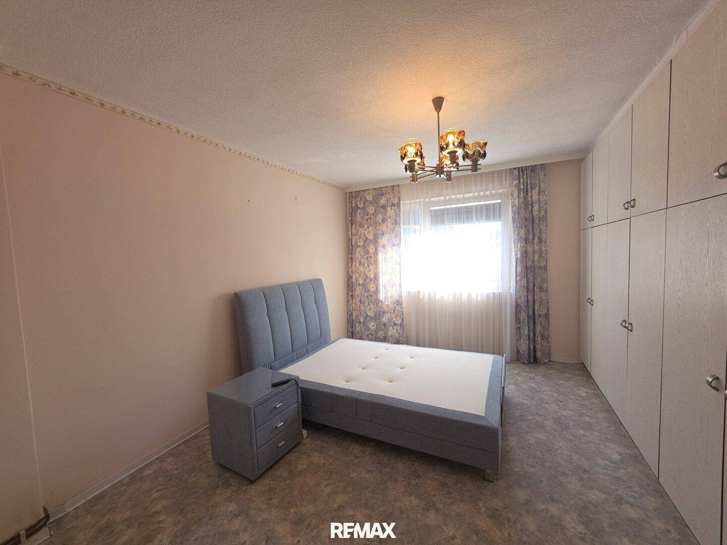 Schlafzimmer mit Doppelbett, Einbauschränken und Fenster mit Vorhängen.