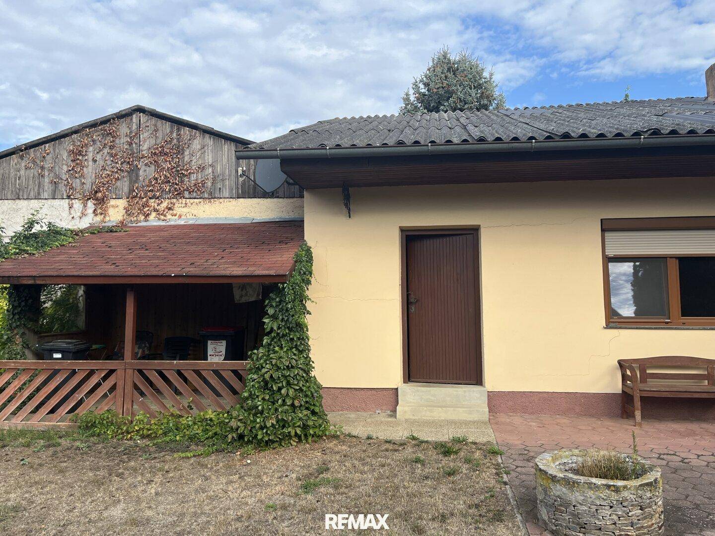 Rückseite des Hauses mit einem überdachten Außenbereich und einem trockenen Rasen.