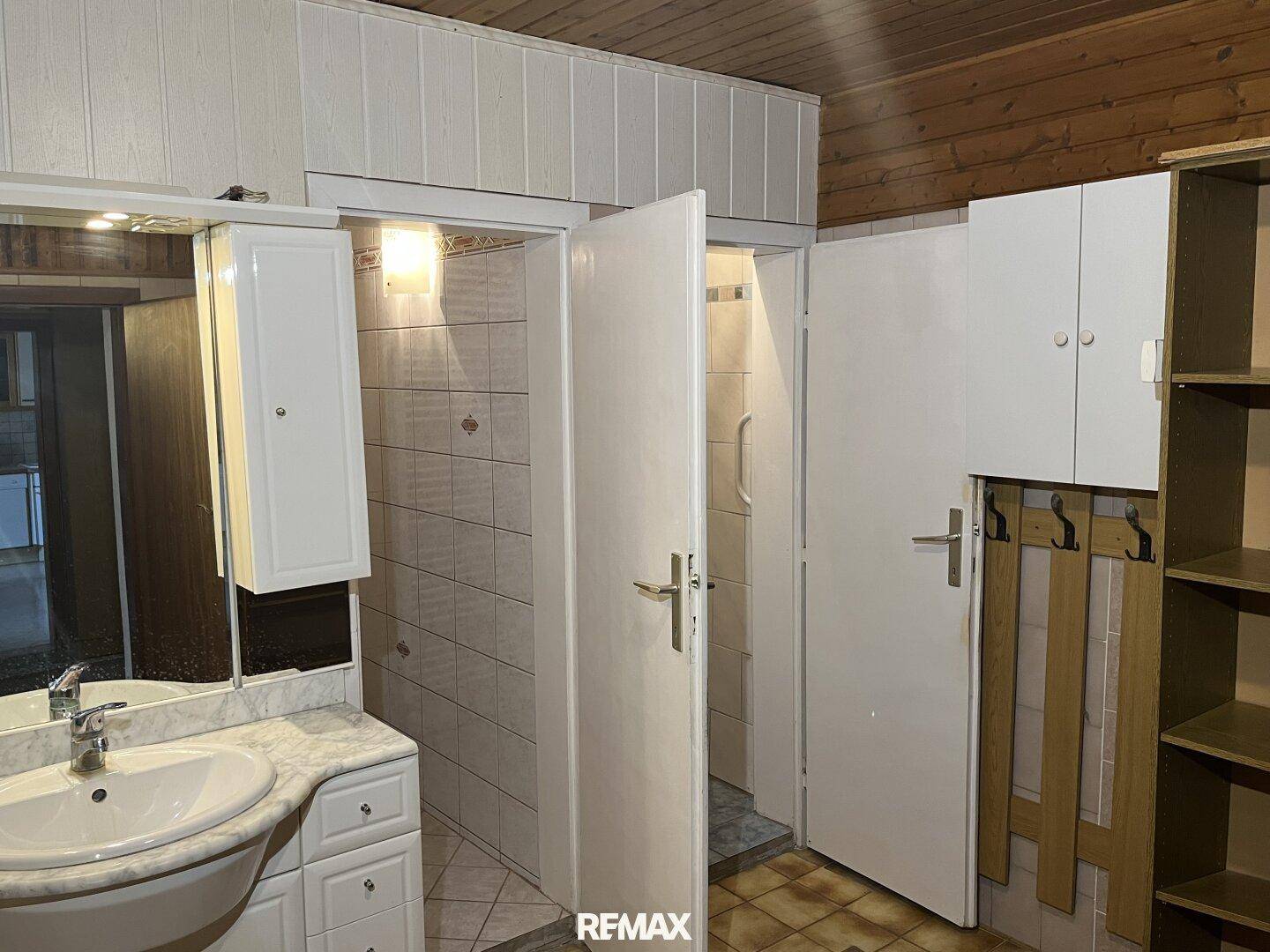 Badezimmer mit Waschbecken, Spiegelschrank und Zugang zu einer Duschkabine.