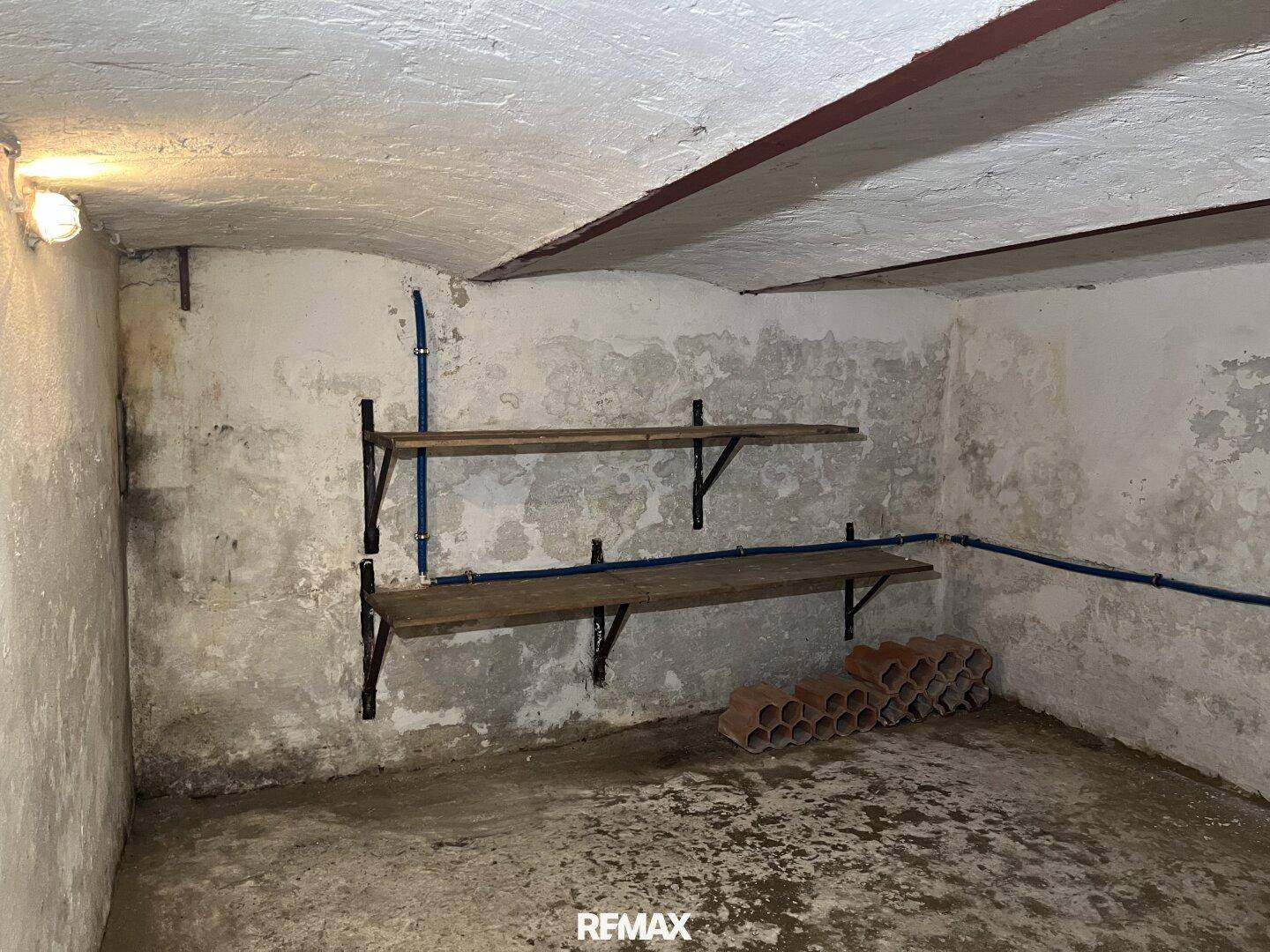 Kellerraum mit einfachen Regalen und Betonboden, ideal als Lagerfläche oder Weinkeller.