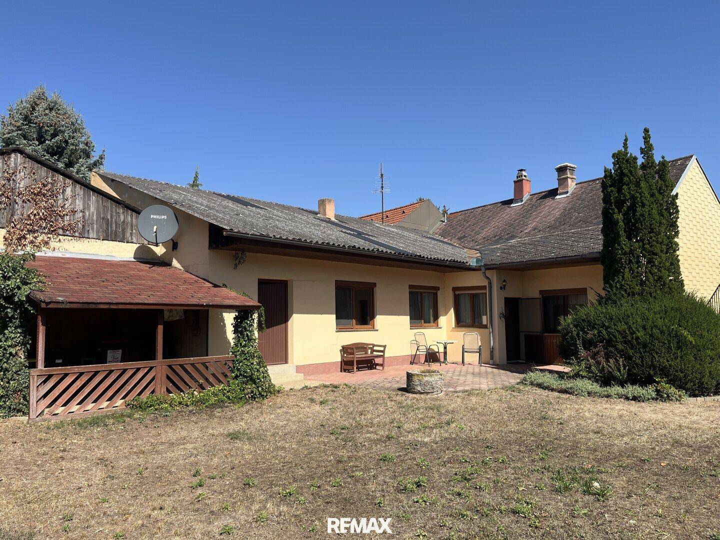 Hinterhof mit gepflasterter Terrasse, Sitzgelegenheiten und einem überdachten Bereich im Garten.