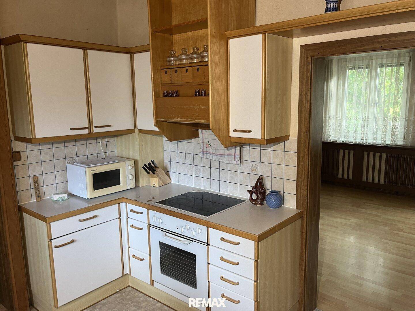 Küchenzeile mit Herd, Backofen, Mikrowelle und gefliestem Spritzschutz in traditionellem Stil.