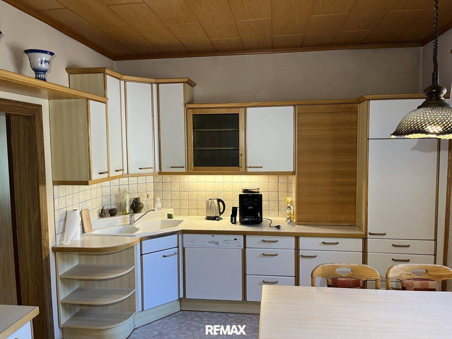 Traditionelle Küche mit Holz- und weißen Schrankfronten, integriertem Geschirrspüler und Essbereich.