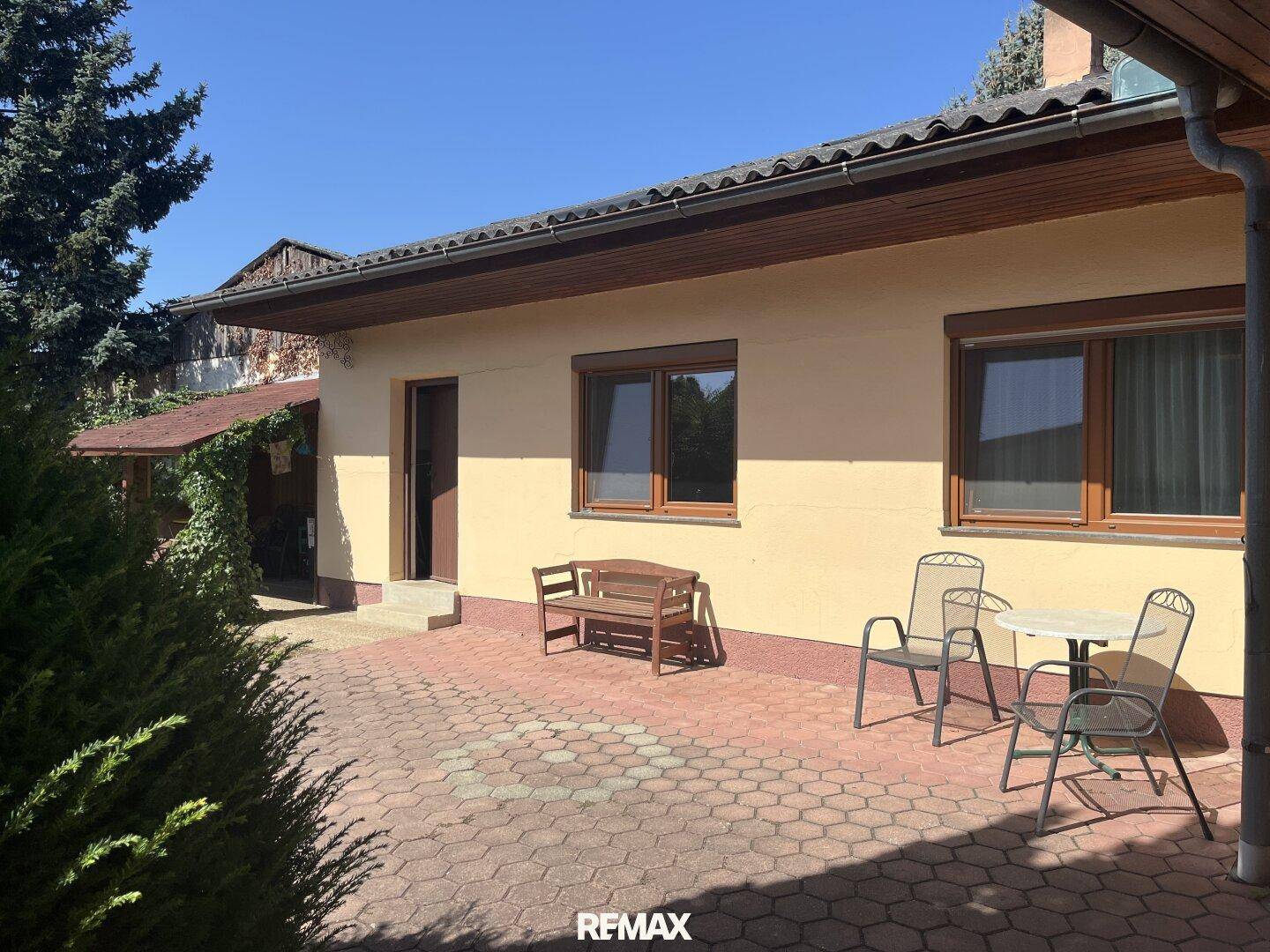 Gepflasterte Terrasse mit Gartenmöbeln und direktem Zugang zum Haus.