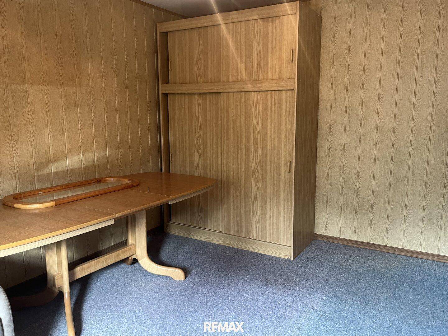 Esszimmer mit Holztäfelung an den Wänden, einem Esstisch und einem Kleiderschrank.