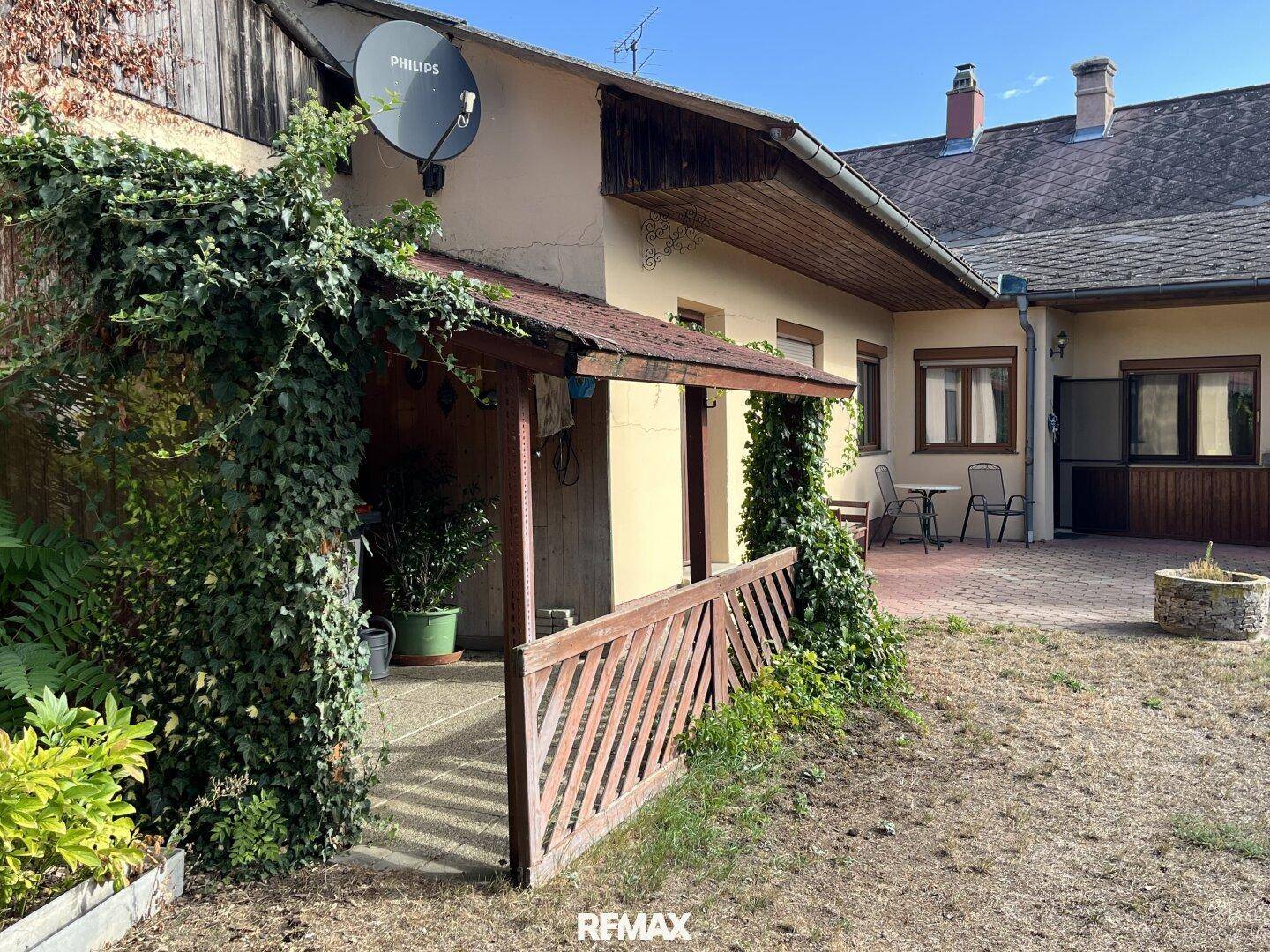 Überdachter Terrassenbereich mit Holzgeländer und Zugang zum Garten.