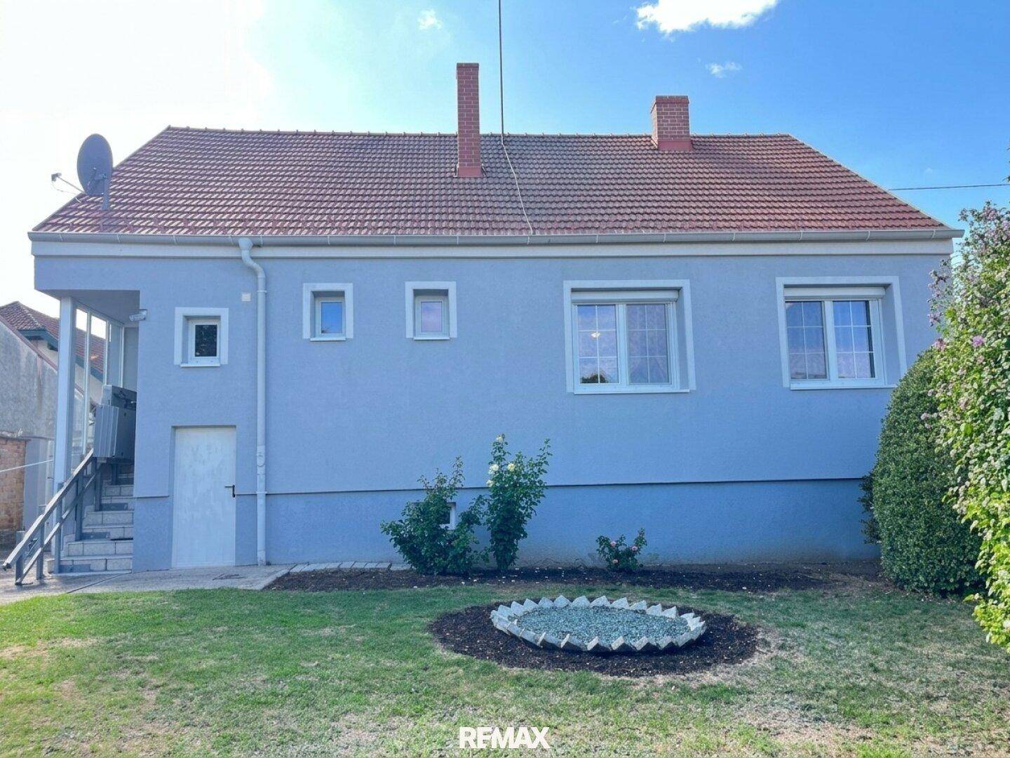 Rückseite des Hauses mit Garten, Rasenfläche und dekorativer Bepflanzung.