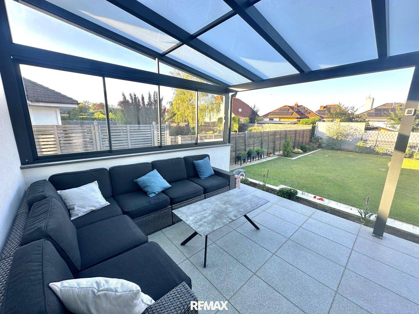 Geräumige überdachte Terrasse mit bequemer Lounge-Sitzgruppe und Blick auf den Garten.