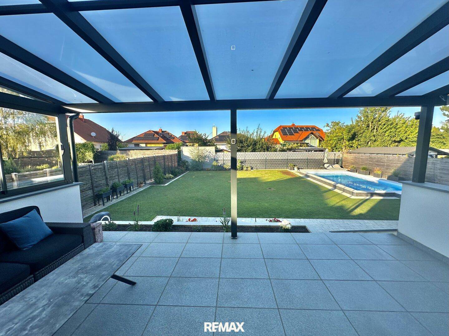 Überdachte Terrasse mit Fliesenboden bietet einen weiten Blick über den Garten und den Swimmingpool.