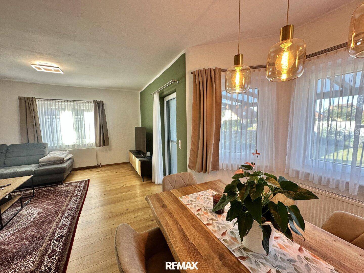 Heller Wohn- und Essbereich mit Holzboden, modernem Esstisch und großen Fenstern.