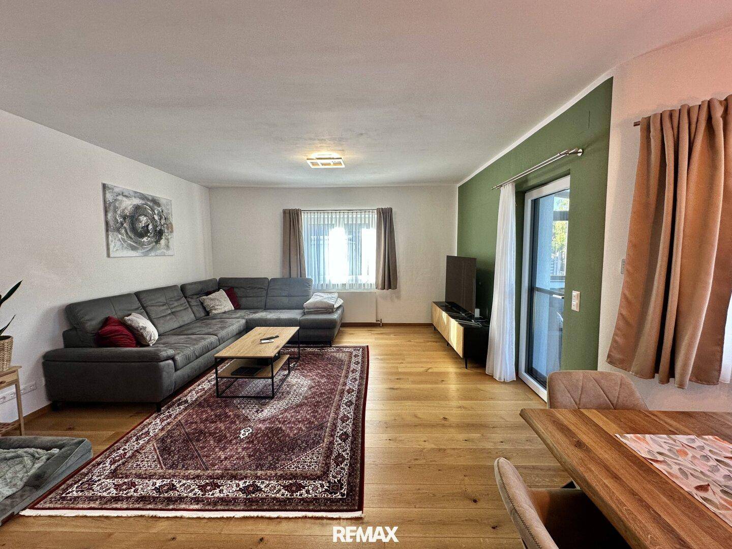 Gemütlicher Wohnbereich mit großem Ecksofa, Teppich und Holzboden, offen zum Essbereich.