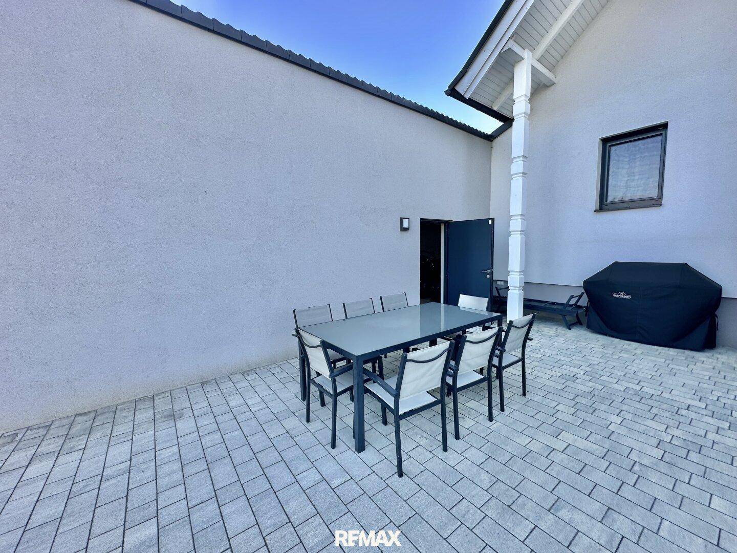Geräumige gepflasterte Terrasse mit Esstisch und Grillbereich neben dem Haus.