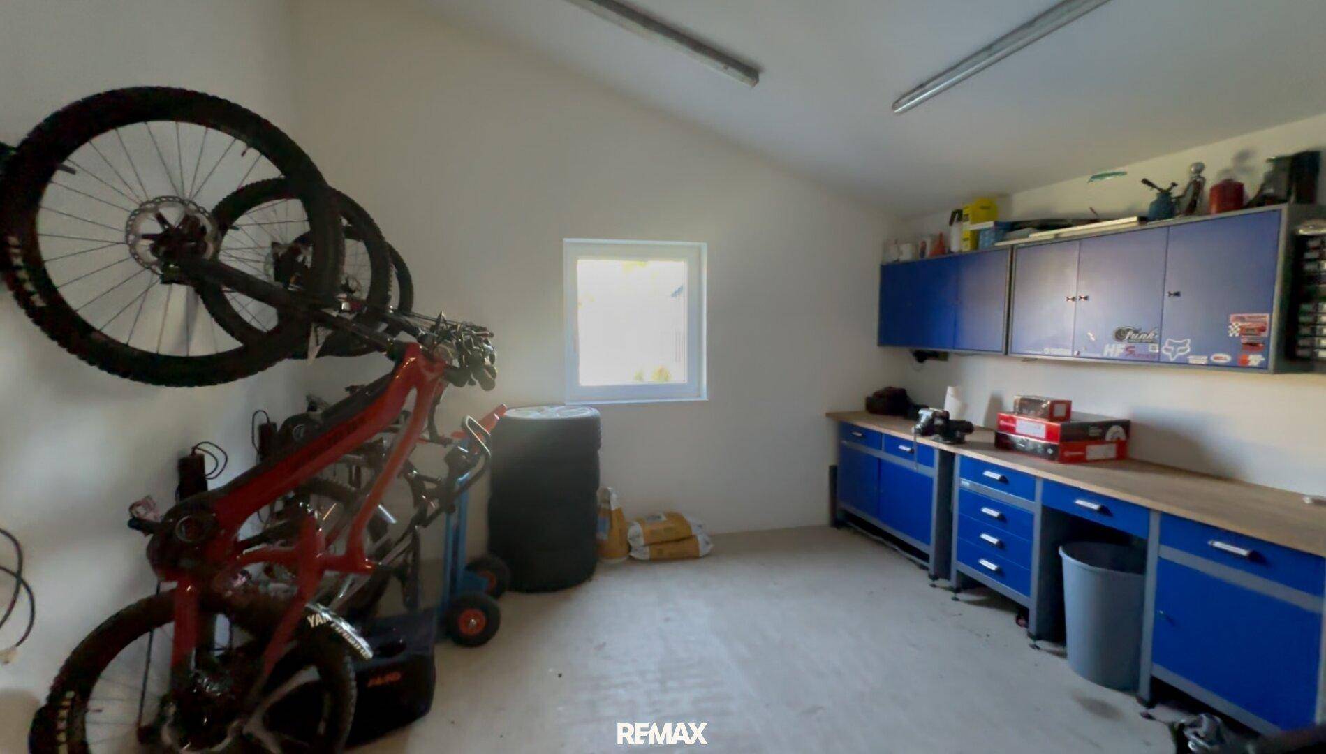 Werkstattbereich in der Garage mit blauen Schränken, Arbeitsplatte und Fahrradaufhängung.